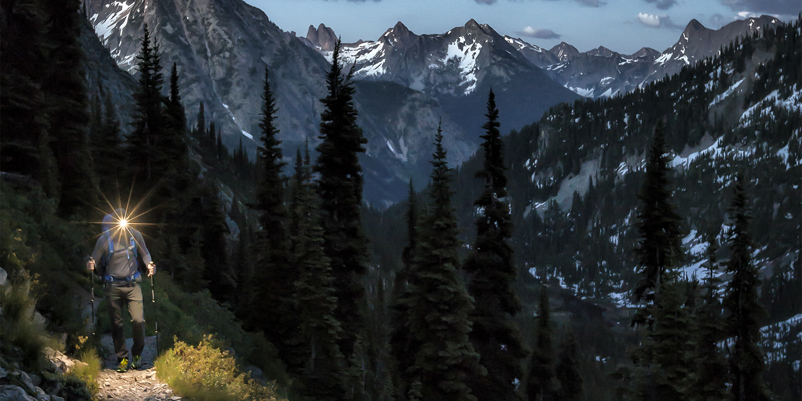 A hiker hikes along a trail by headlamp, in the North Cascades, Washington State.